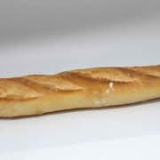 A baguette resting on a white surface, showcasing its long shape and crusty exterior