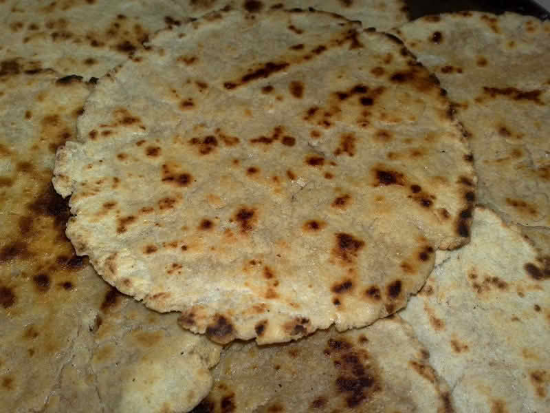 Close-up of bhakri flatbreads layered on top of one another, showcasing their texture and golden-brown color