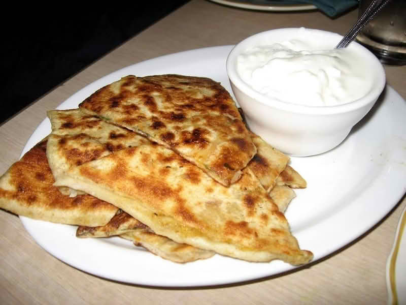 A plate of Afghan Bolani accompanied by a serving of sour cream