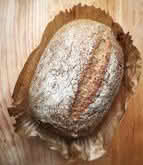 A loaf of bread resting on a rustic wooden table, showcasing its golden crust and inviting texture