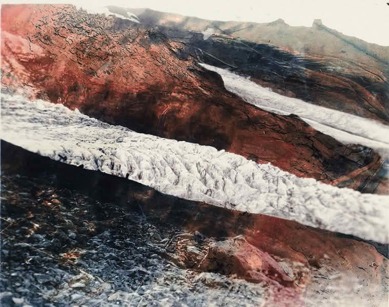 A glacier descending near Hof, with water cascading over the rugged mountain landscape