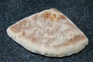 A piece of soda bread resting on a wooden table, showcasing its rustic texture and golden-brown crust